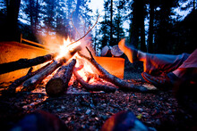 A Camper Dries Her Foot Next To The Flames Of Their Campfire.