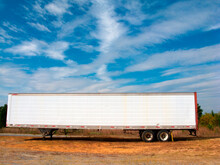 Old Trailer With White Clouds And Blue Sky In Background.