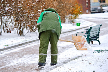 Wall Mural - Man clear snow with shovel from sidewalk during snow storm, cleans footpath from snow during blizzard. Utility worker shoveling snow on city street. Janitor clearing snowy walkway with shovel