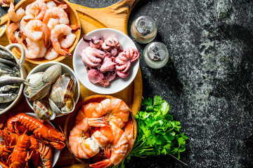 Wall Mural - Various seafood on a round cutting Board with herbs and spices.