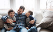 © Grady R/peopleimages.com - Hug, happy and portrait of father with children on the sofa for love, care and relax in family home. Smile, funny and dad with boy kids for quality time, affection and comedy on the couch of a house