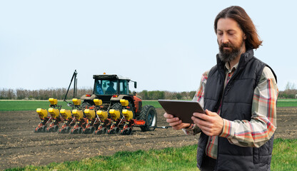 Sticker - Farmer with a digital tablet on the background of an agricultural tractor with seeding machine	