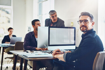 Leinwandbilder - Portrait, mature and business man by computer in office workplace. Planning, pc or confident male employee working on marketing report, advertising proposal or sales project with coworkers in company