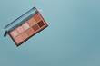 Top view eyeshadow rose gold glitter and beige mauve and brown matte palette on blue background. Cosmetic banner with copy space