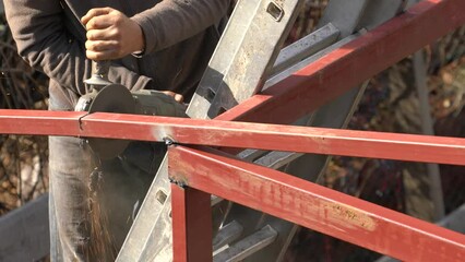 Wall Mural - For the construction of an iron construction vineyard house (pergola) in the green area, the master assembles the roof of the building and grinding sparks when the iron cutting