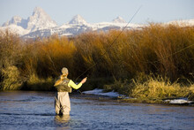 Woman Fishing At Sunset With Mountains In Background, Idaho