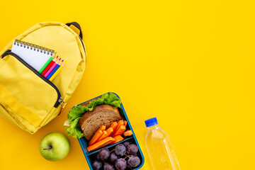 Healthy school lunch box with fruits and backpack, top view