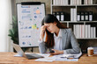 © Nuttapong punna - Woman who is tired and overthinking from working with tablet and laptop at modern office...