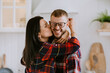 © Iona - Happy couple celebrating success at home. Young Italian man in glasses eyes closed excited, winner. Brunette hisp[anic girl kissing husband sad him that she is pregnant. Happy family. Triumph.