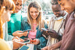 © Davide Angelini - Happy group of multiracial teens using smart mobile phone outdoors - Diverse university students watching smartphones in college campus - Millenial people having fun on city street - Youth culture
