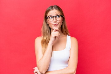 Wall Mural - Young beautiful woman isolated on red background thinking an idea while looking up