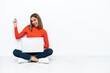 © luismolinero - Young caucasian woman sitting on the floor with a laptop making guitar gesture