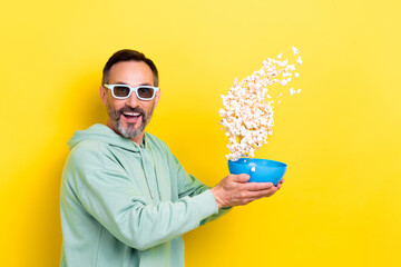 Sticker - Photo of old retired middle mature age man wear khaki green hoodie throw up bowl with popcorn have fun cinema isolated on yellow color background