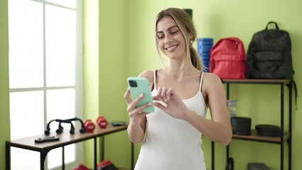 Wall Mural - Young blonde woman smiling confident using smartphone at sport center