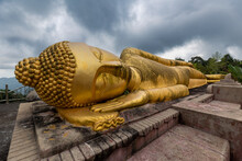 Closeup Of Giant Golden Statue Of Sleeping Buddha On Hilltop Under Cloudy Sky, Samui, Thailand