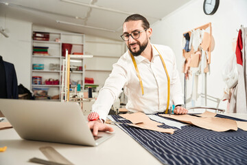 Wall Mural - Pleased tailor working on laptop in workshop