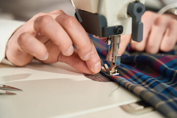 Wall Mural - Experienced tailor is threading sewing machine before work