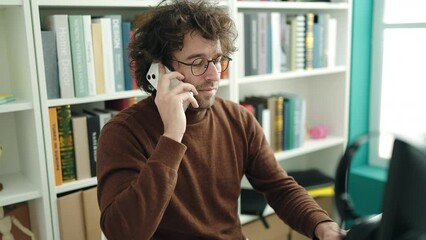 Poster - Young hispanic man student talking on smartphone using computer at library university