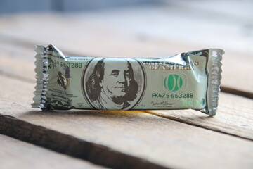 Wall Mural - One hundred dollars in the form of a candy on a wooden background. Money background.