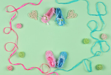 Greeting decorations : openwork shoes, ribbons, balls and hearts from rattan for congratulating newborn twins a baby girl and a baby boy on a light green background .Top view . Free copy space