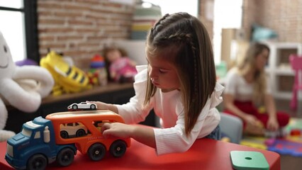 Poster - Teachers and toddler playing with cars toy sitting on table at kindergarten