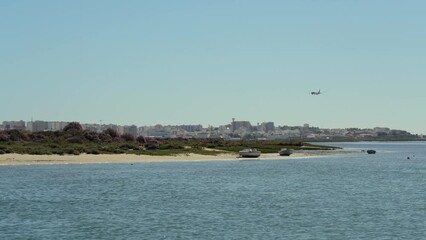 Canvas Print - Beautiful sea view of the Ria Formosa park of Faro. landing plane at airport with a view of city