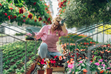 Wall Mural - Woman working in a greenhouse flower plant nursery