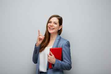 Wall Mural - Woman teacher or smiling student girl pointing finger up isolated portrait..