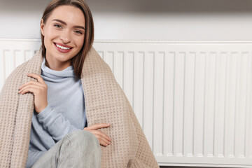 Poster - Woman with blanket near heating radiator indoors, space for text