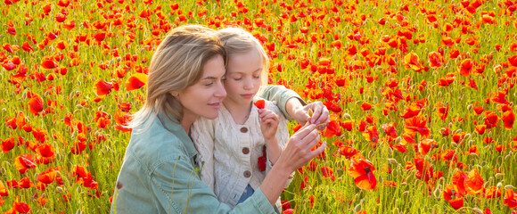 Mother and daughter on the poppies field background. Spring family banner. Beautiful child girl with young mother are wearing casual clothes in field of poppy flowers. Family on spring poppy field.