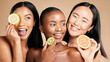 © Jade M/peopleimages.com - Face, fruits and women in portrait with cream for facial care, beauty and natural cosmetics isolated on studio background. Sunscreen, vegan and different skin with skincare, moisturizer and playful
