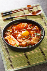 Poster - Sundubu jjigae is a Korean stew made with soft tofu, kimchi, pork belly, onion and spices closeup on the bowl on the table. Vertical