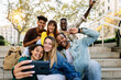© Xavier Lorenzo - Multiracial young happy group of student friends taking selfie portrait together using mobile phone outdoors