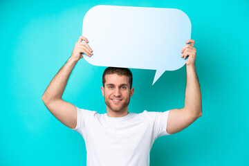 Wall Mural - Young caucasian man isolated on blue background holding an empty speech bubble