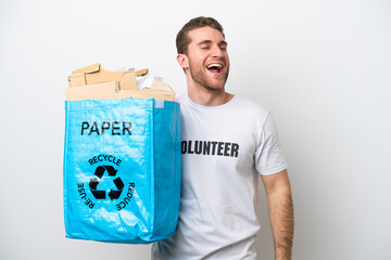 Wall Mural - Young caucasian man holding a recycling bag full of paper to recycle isolated on white background laughing