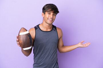 Wall Mural - Young man playing rugby isolated on purple background extending hands to the side for inviting to come