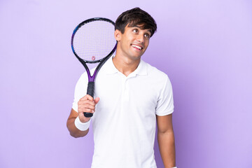 Handsome young tennis player man isolated on ocher background thinking an idea while looking up