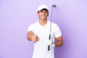 Young caucasian man isolated on purple background playing golf and pointing to the front