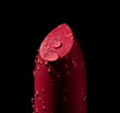 Close up red lipstick covered with water droplets. Red lipstick isolated on black background. Selective focus
