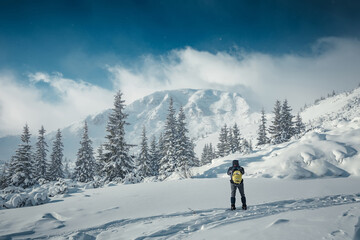 Fototapete - Incredible winter nature landscape. Alone man in snow covered mountain. Hiker, photographer on the or alpiniston run training outdoors active fit lifestyle. Snowy mountain scenery with snowfall