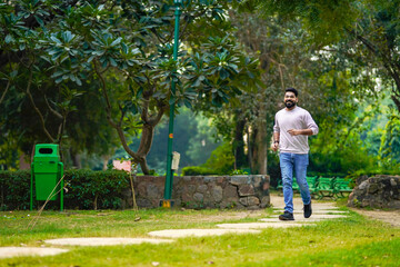 Wall Mural - Young indian man running or jogging at park.