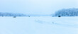 Panorama of ice fishing trailers and house on a Minnesota lake with trees covered in hoar frost