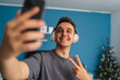© Dusan - A portrait photos of a young guy listening to music on his wireless headphones and taking selfies with headphones while listening to music in his house during the day