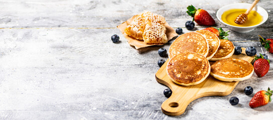 Poster - Homemade pancakes on a cutting board with honey and berries. 