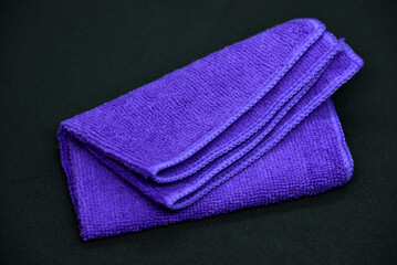 A cloth for wiping. Purple cloth on a black background. Towel.