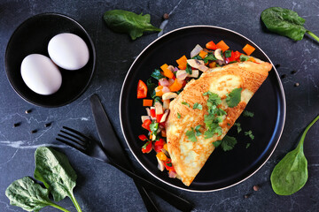 Poster - Healthy vegetable loaded omelette. Top view table scene over a dark stone background.