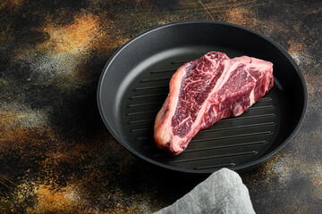 Wall Mural - Raw fresh dry aged beef T-bone steak, in frying cast iron pan, on old dark rustic background