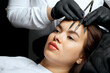 Cosmetician forming the shape of the brows before the permanent tattoo procedure