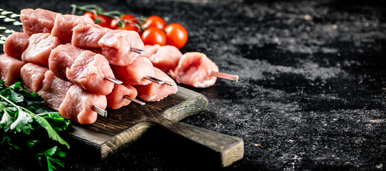 Sticker - Pork kebab raw on a cutting board with tomatoes and parsley. 