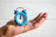 © Iryna - Classic arrow blue alarm clock on a man hand on white background, concept of the passage of time